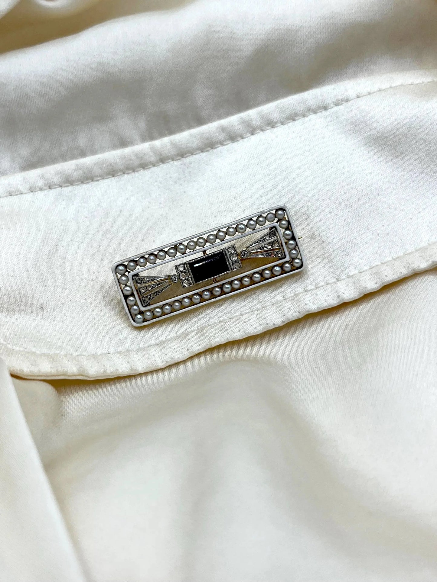A rectangular brooch with sapphire, pearls and diamonds in gold and platinum, modelled on a white shirt pocket