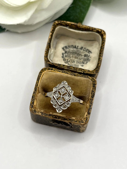 An open cluster ring with diamonds in platinum and yellow gold, in an antique ring box