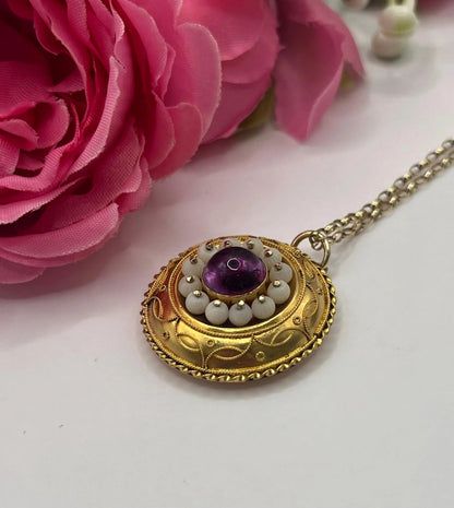 A round etruscan style pendant with a cabochon amethyst and carved coral in yellow gold, with a gold chain