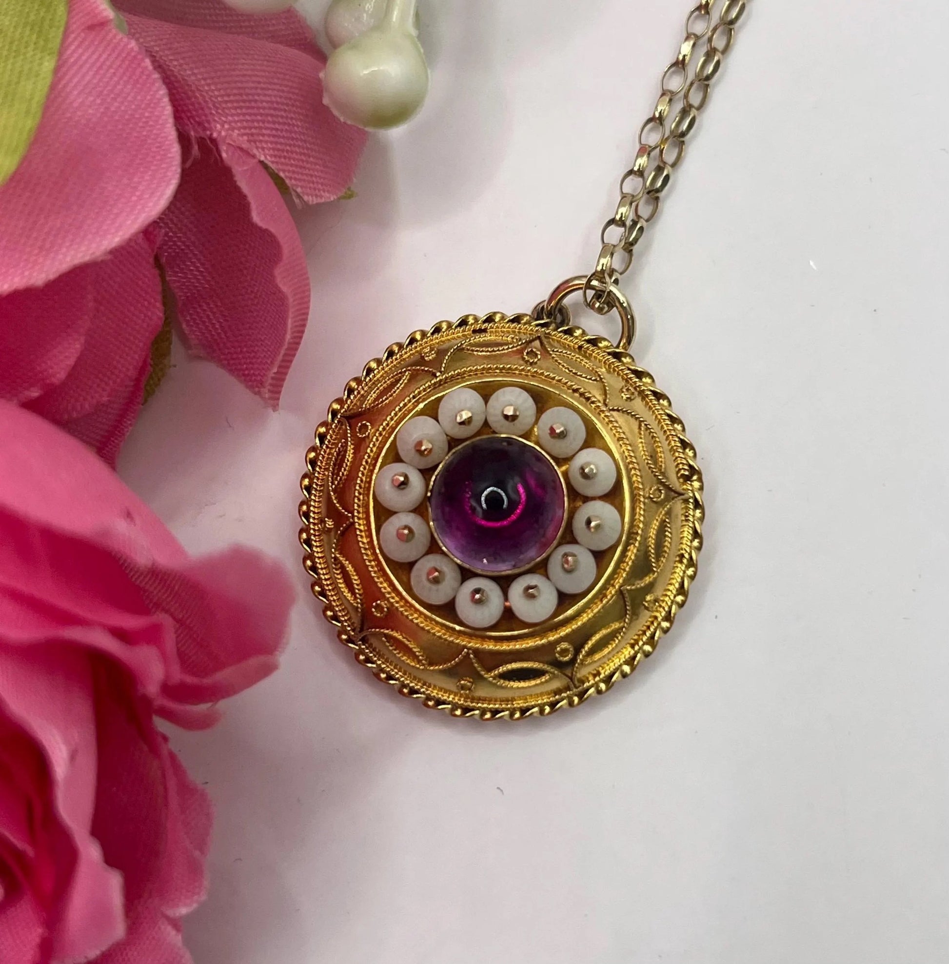 A round etruscan style pendant with a cabochon amethyst and carved coral in yellow gold, with a gold chain