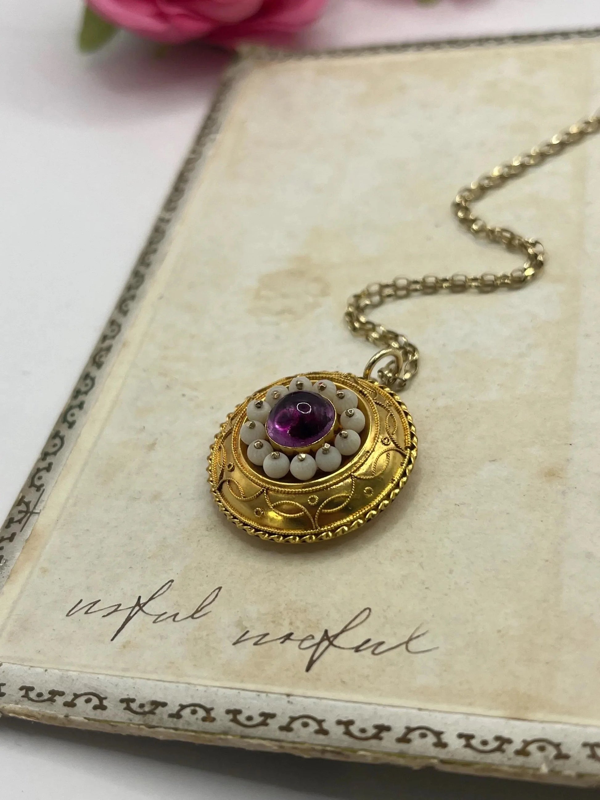 A round etruscan style pendant with a cabochon amethyst and carved coral in yellow gold, with a gold chain