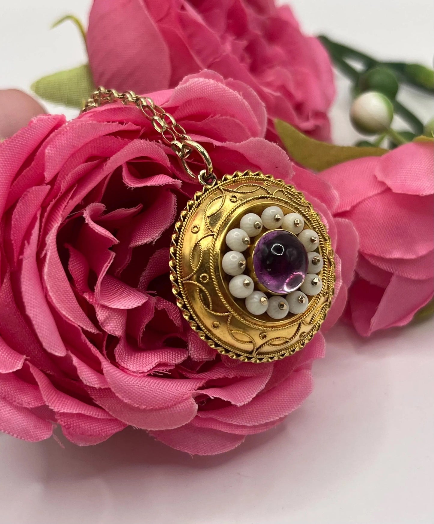 A round etruscan style pendant with a cabochon amethyst and carved coral in yellow gold, with a gold chain