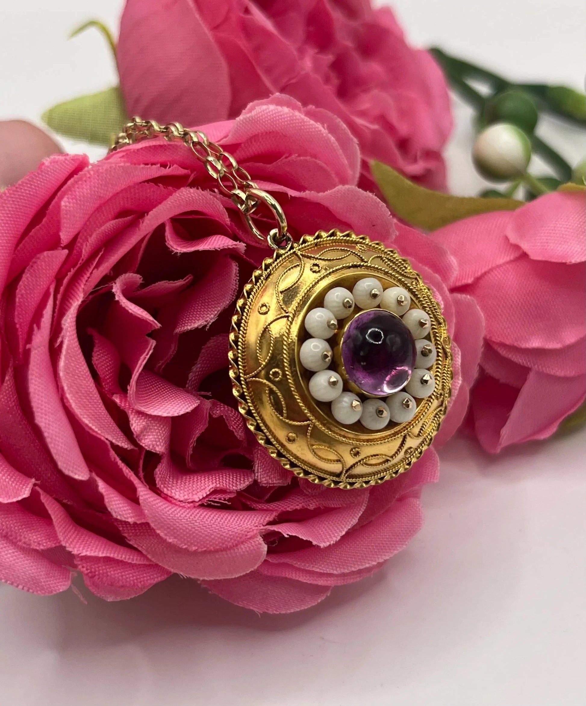 A round etruscan style pendant with a cabochon amethyst and carved coral in yellow gold, with a gold chain