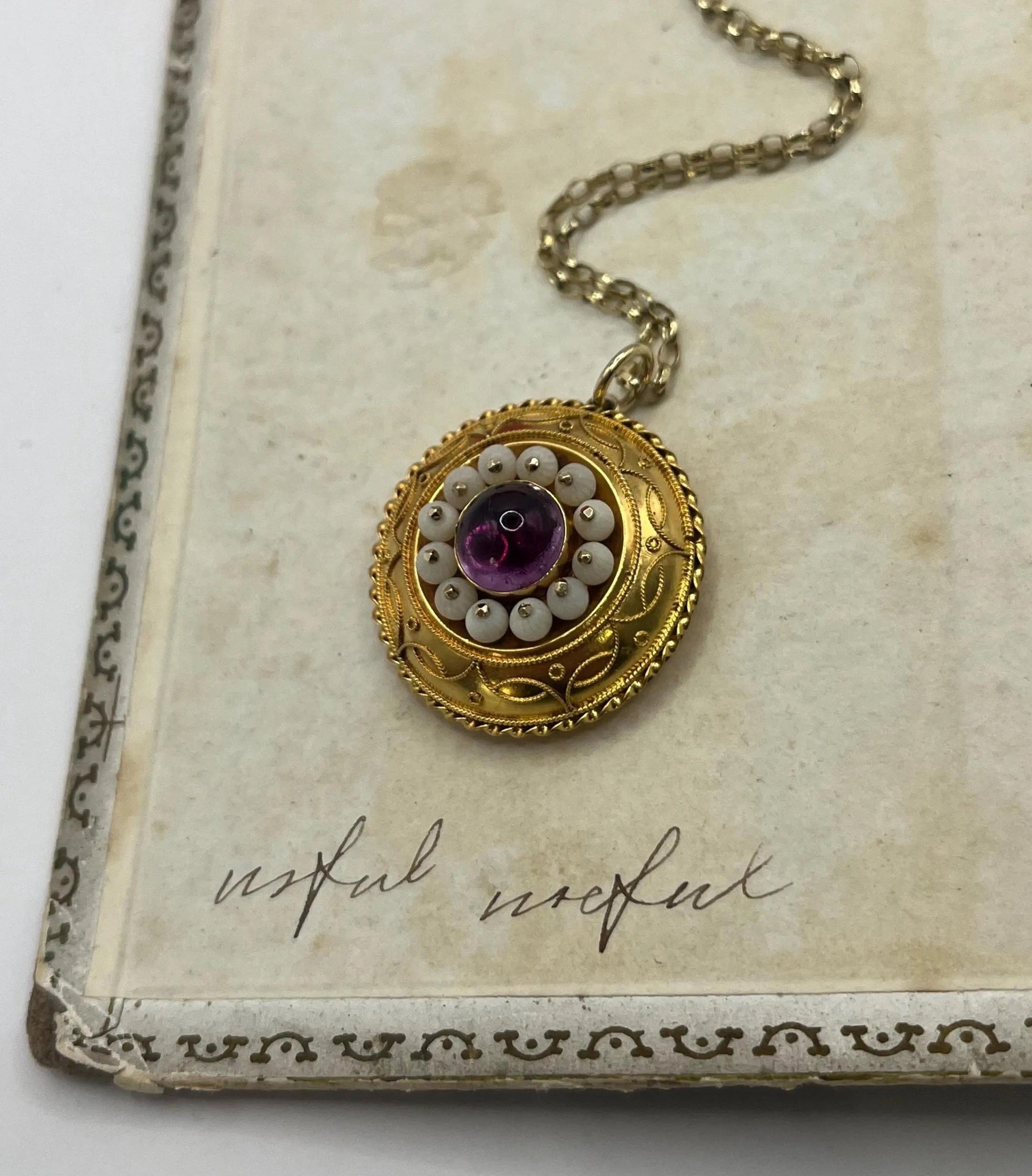 A round etruscan style pendant with a cabochon amethyst and carved coral in yellow gold, with a gold chain