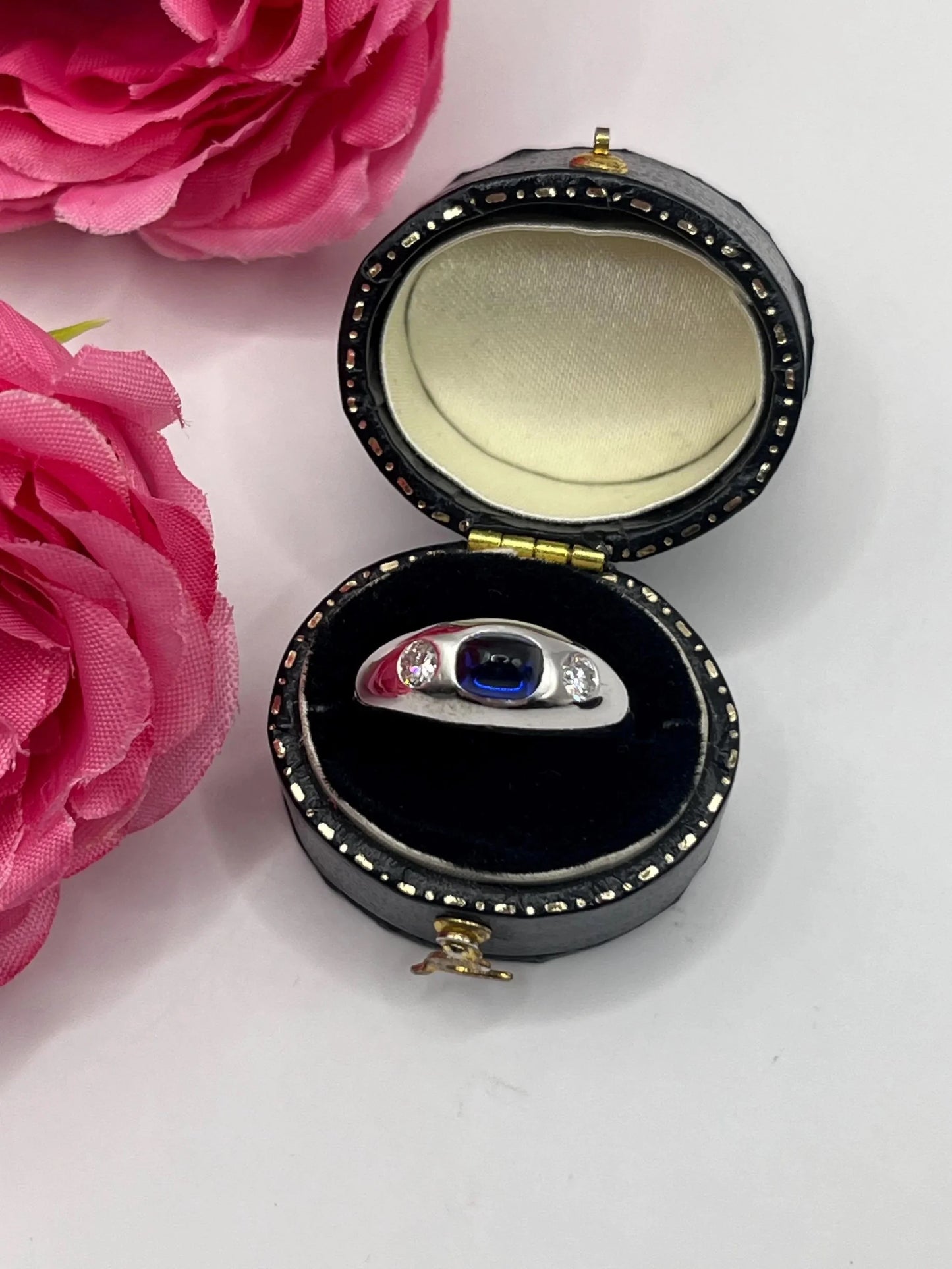 A cabochon sapphire and round diamond three stone band ring in white gold, in a ring box