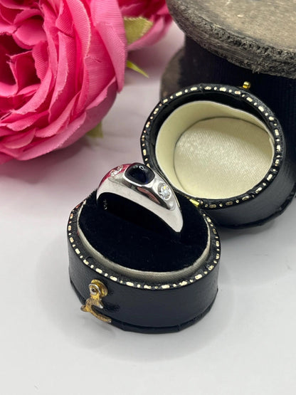A cabochon sapphire and round diamond three stone band ring in white gold, in a ring box