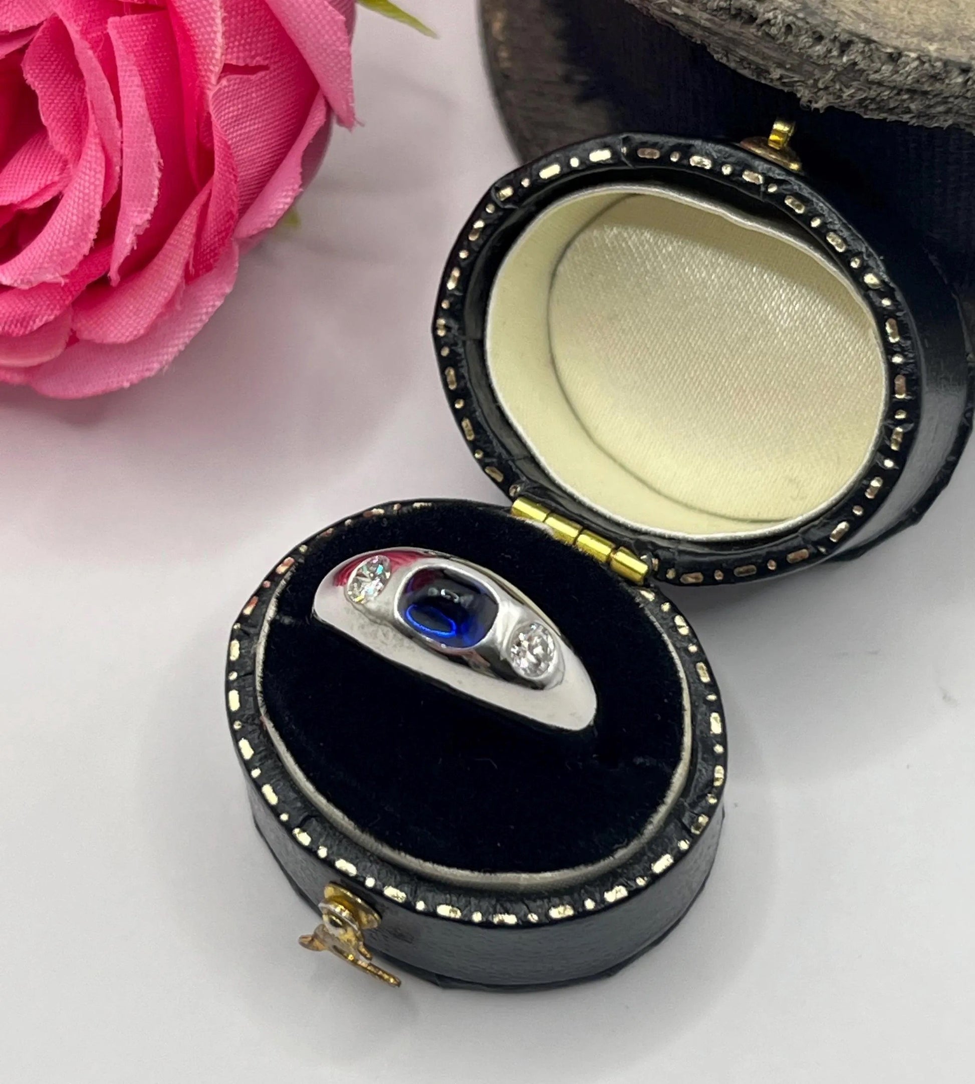 A cabochon sapphire and round diamond three stone band ring in white gold, in a ring box