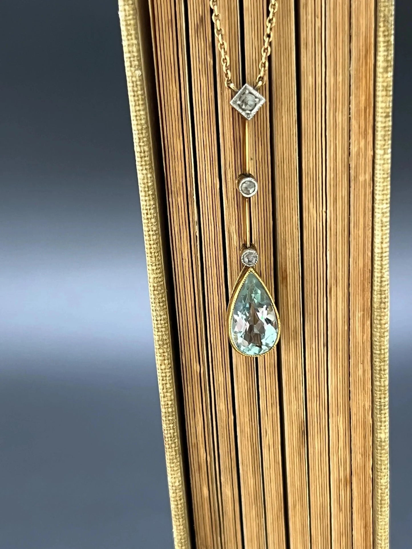 A pear shaped aquamarine and diamond drop pendant necklace in yellow gold