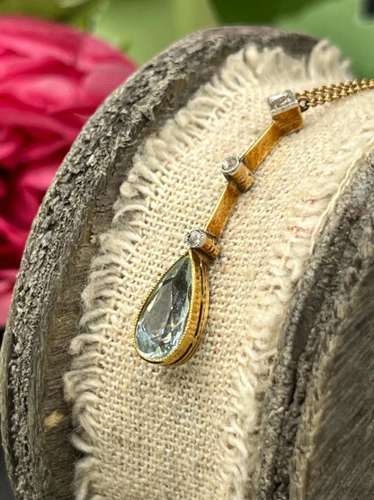 A pear shaped aquamarine and diamond drop pendant necklace in yellow gold