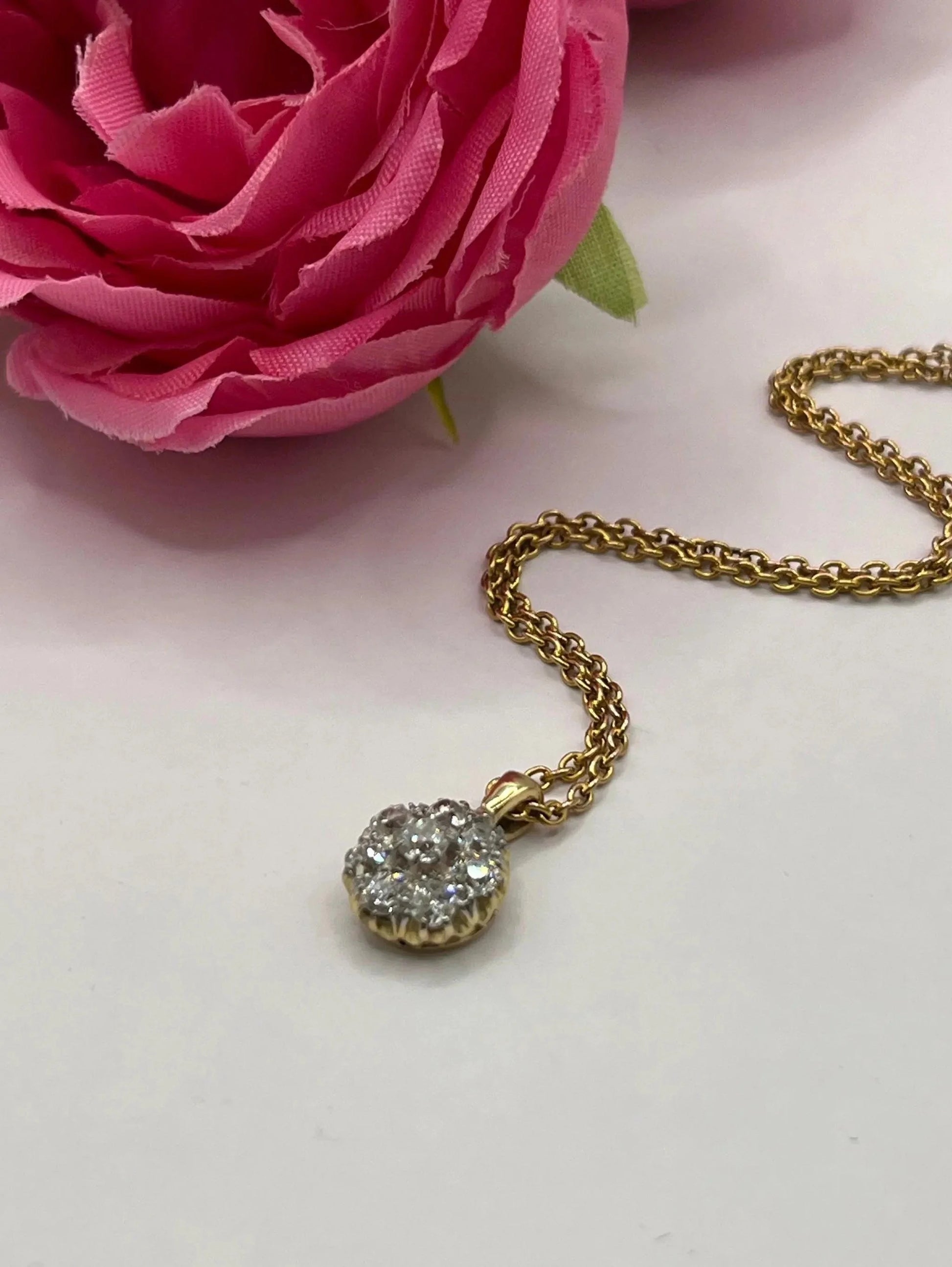 A diamond cluster pendant in yellow and white gold with a yellow gold chain