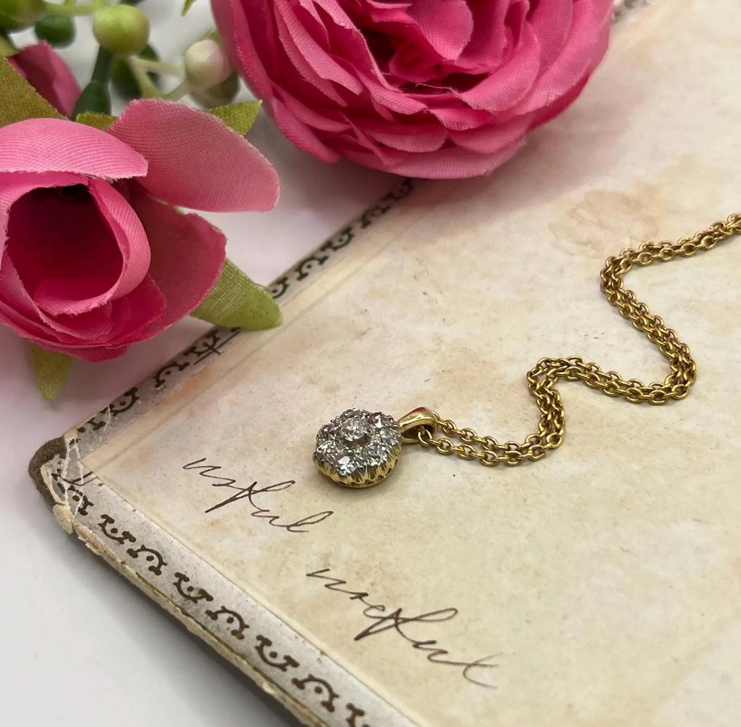 A diamond cluster pendant in yellow and white gold with a yellow gold chain