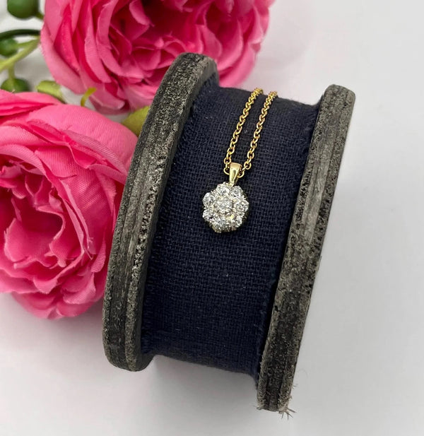 A diamond cluster pendant in yellow and white gold with a yellow gold chain