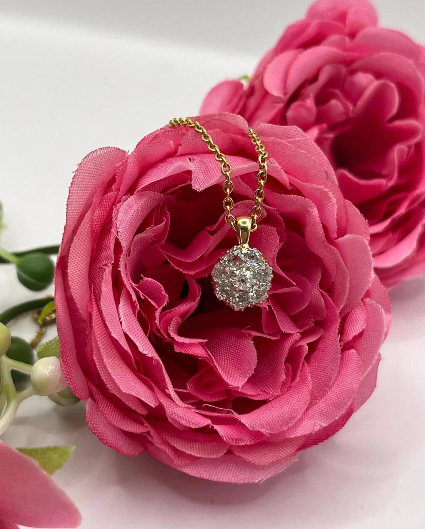 A diamond cluster pendant in yellow and white gold with a yellow gold chain