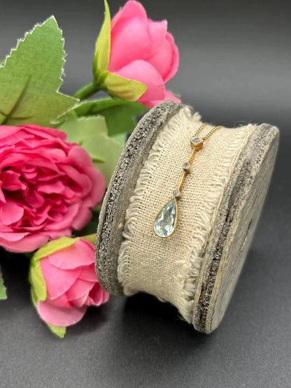 A pear shaped aquamarine and diamond drop pendant necklace in yellow gold