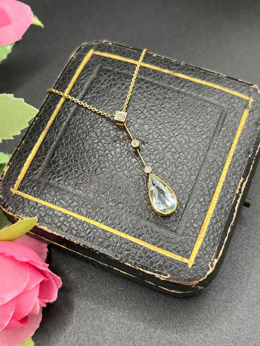 A pear shaped aquamarine and diamond drop pendant necklace in yellow gold