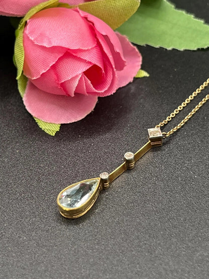 A pear shaped aquamarine and diamond drop pendant necklace in yellow gold