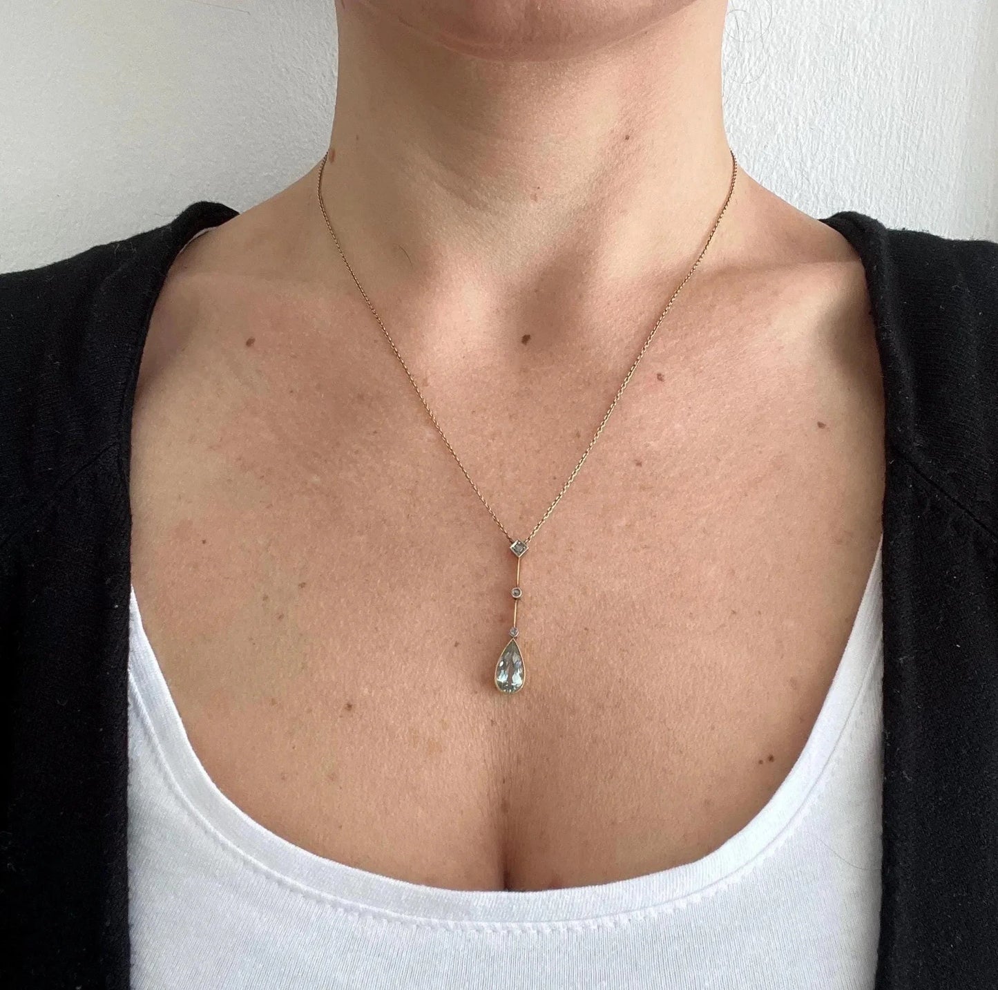 A pear shaped aquamarine and diamond drop pendant necklace in yellow gold, modelled by a woman