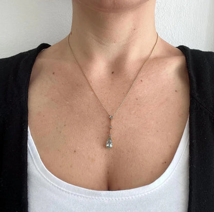 A pear shaped aquamarine and diamond drop pendant necklace in yellow gold, modelled by a woman
