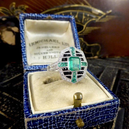 Emerald, onyx and diamond cluster ring in platinum.