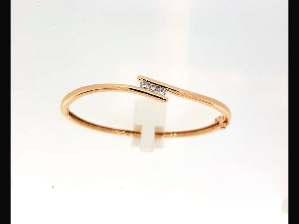 Diamond bangle; Three round brilliant cut diamonds totaling 0.33 carats tension set into an 18ct rose gold bangle with a double safety catch