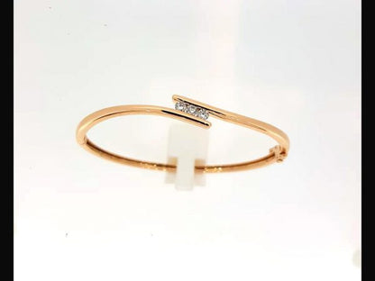 Diamond bangle; Three round brilliant cut diamonds totaling 0.33 carats tension set into an 18ct rose gold bangle with a double safety catch