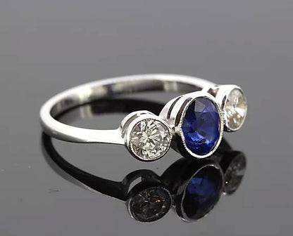 Oval Sapphire and Diamond Trilogy Ring; three-stone ring featuring 1.15ct oval-cut sapphire flanked by two diamonds totaling 0.67cts, 18ct white gold