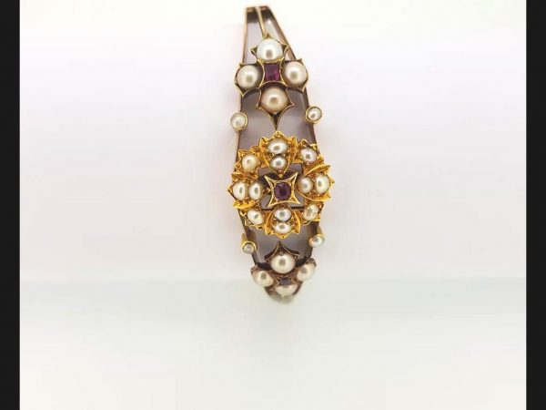 An Antique Edwardian Split Pearl and Ruby Bangle with central floral design and flanked by similar design, on detailed 15ct gold bangle