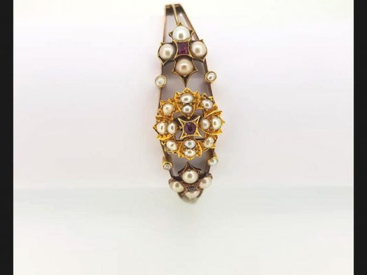 An Antique Edwardian Split Pearl and Ruby Bangle with central floral design and flanked by similar design, on detailed 15ct gold bangle