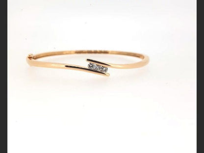 Three round brilliant cut diamonds totaling 0.33 carats tension set into an 18ct rose gold bangle with a double safety catch