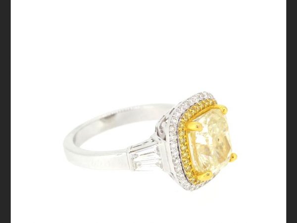Fancy Yellow Diamond Cluster Ring; 4.02 carat central cushion cut yellow diamond within a double halo of yellow and white round cut diamonds, baguette shoulders.