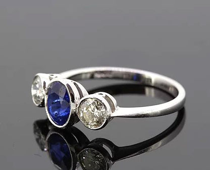 Oval Sapphire and Diamond Trilogy Ring; three-stone ring featuring 1.15ct oval-cut sapphire flanked by two diamonds totaling 0.67cts, 18ct white gold