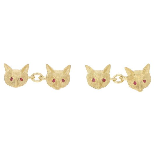 A pair of fox head cufflinks in yellow gold with ruby eyes, on a white background