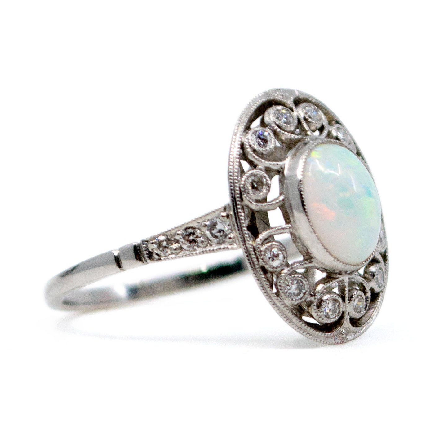 An oval shaped openwork ring with an opal centre and diamonds in swirl settings, in platinum