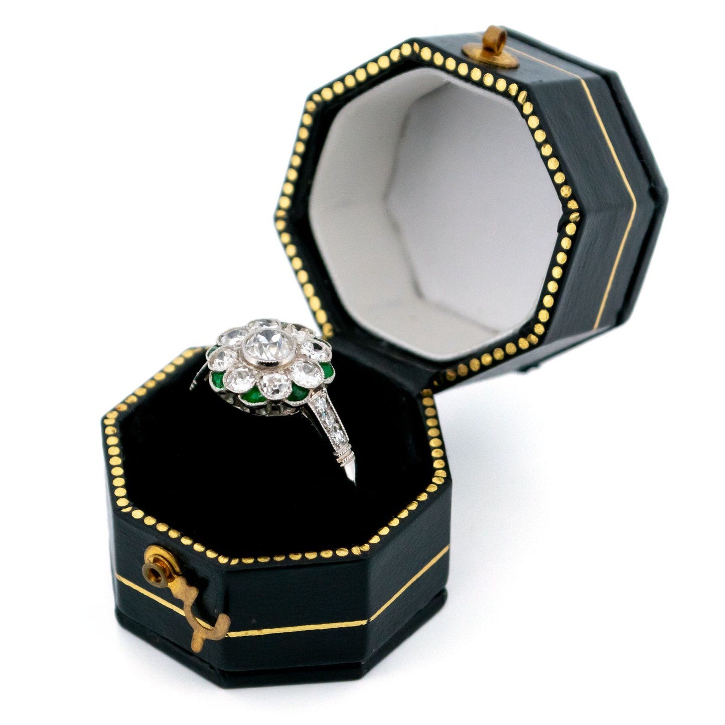 A diamond and emerald daisy cluster ring in platinum, in a ring box