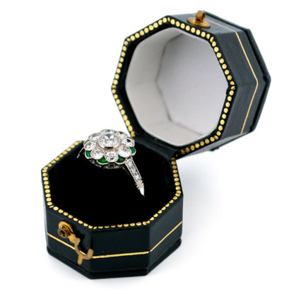 A diamond and emerald daisy cluster ring in platinum, in a ring box