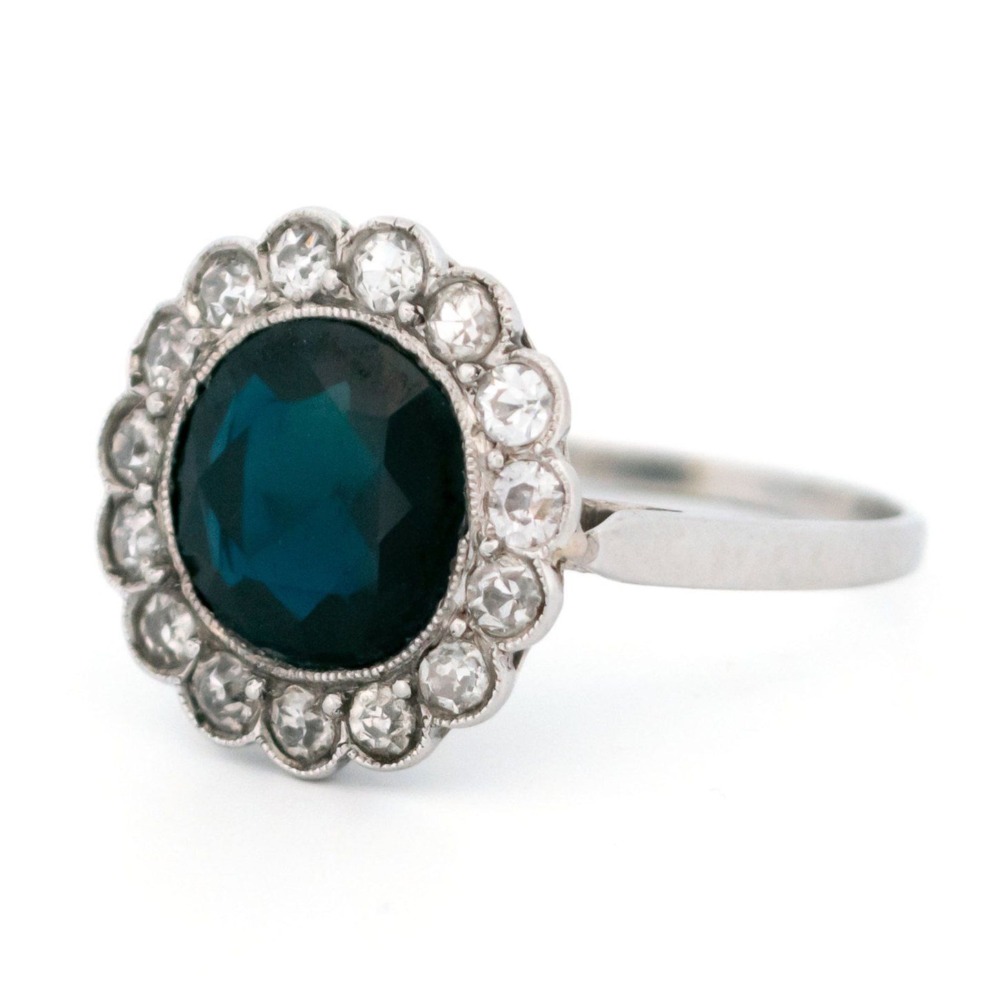 A flower shaped cluster ring set with a central sapphire surrounded by a halo of round diamonds, in platinum