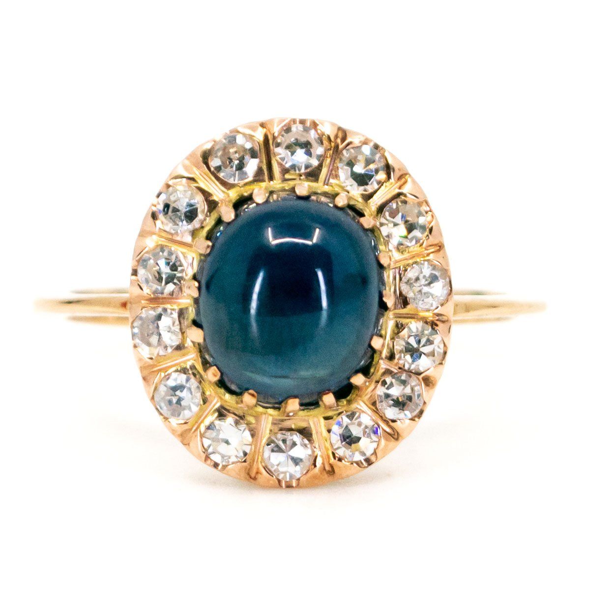 An oval cluster ring with a cabochon sapphire and diamond surround, in yellow gold