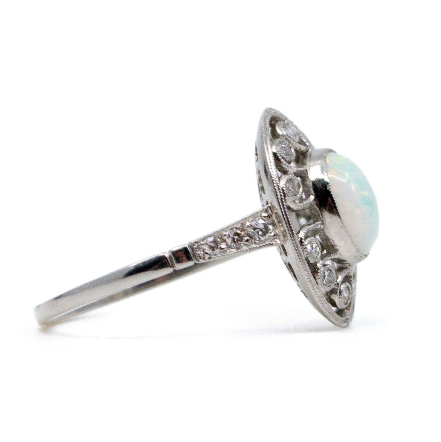 An oval shaped openwork ring with an opal centre and diamonds in swirl settings, in platinum