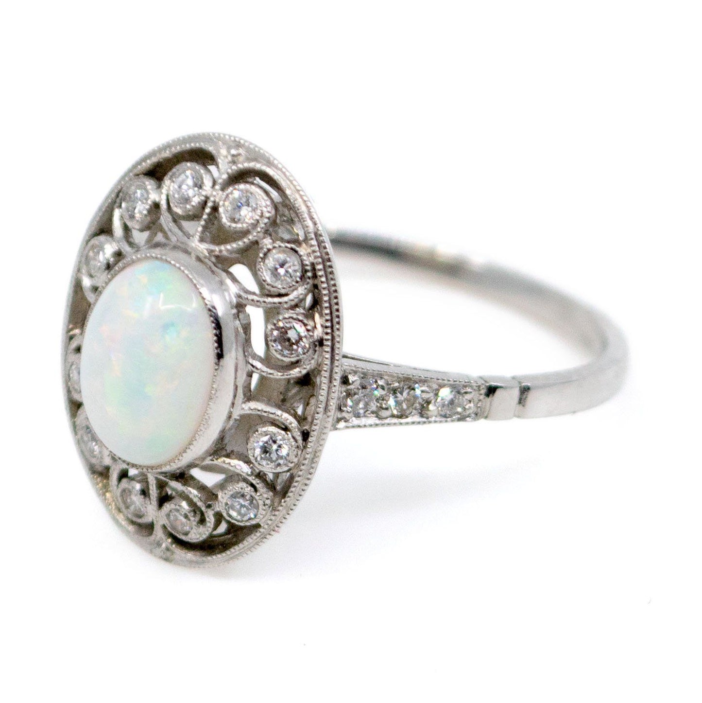 An oval shaped openwork ring with an opal centre and diamonds in swirl settings, in platinum