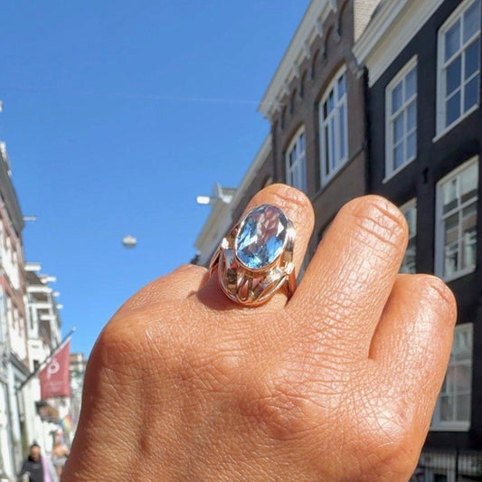 An oval cut aquamarine dress ring in yellow gold, modelled on a hand