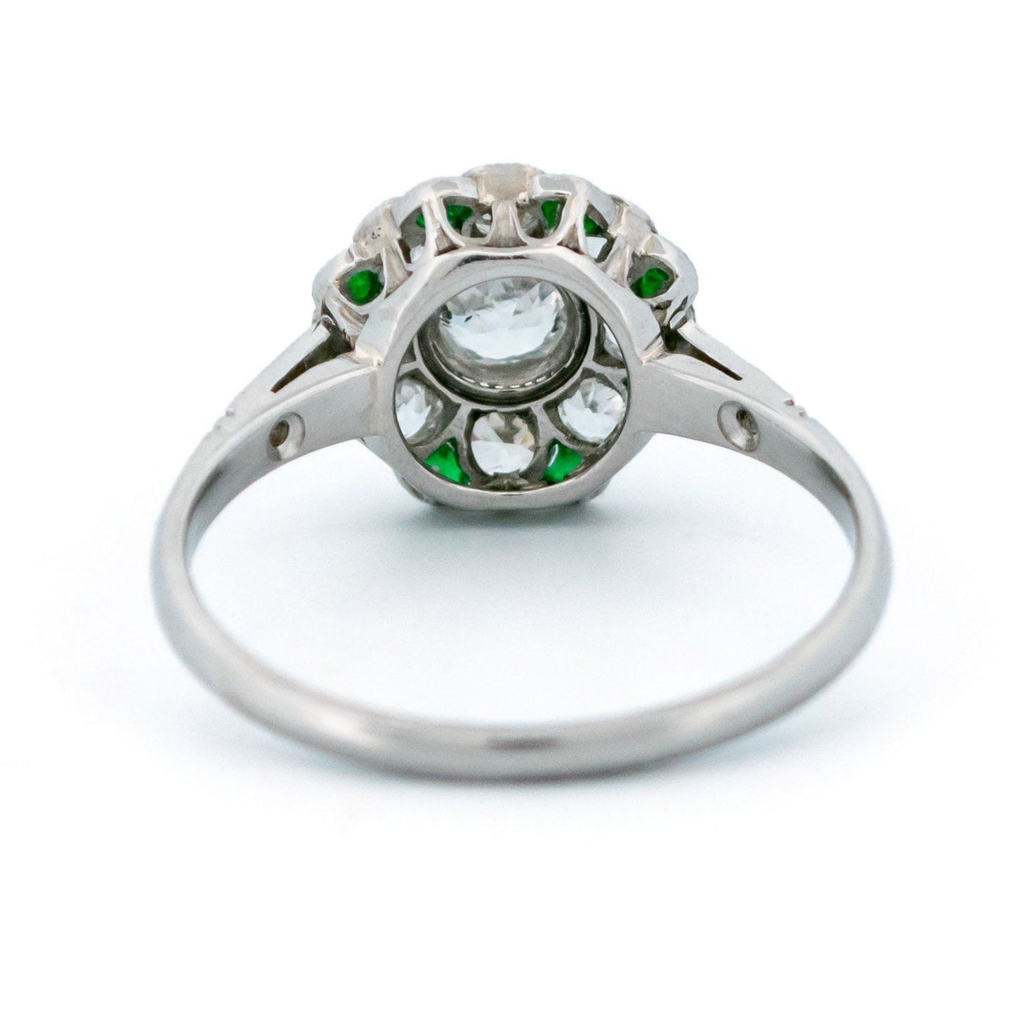 A diamond and emerald daisy cluster ring in platinum