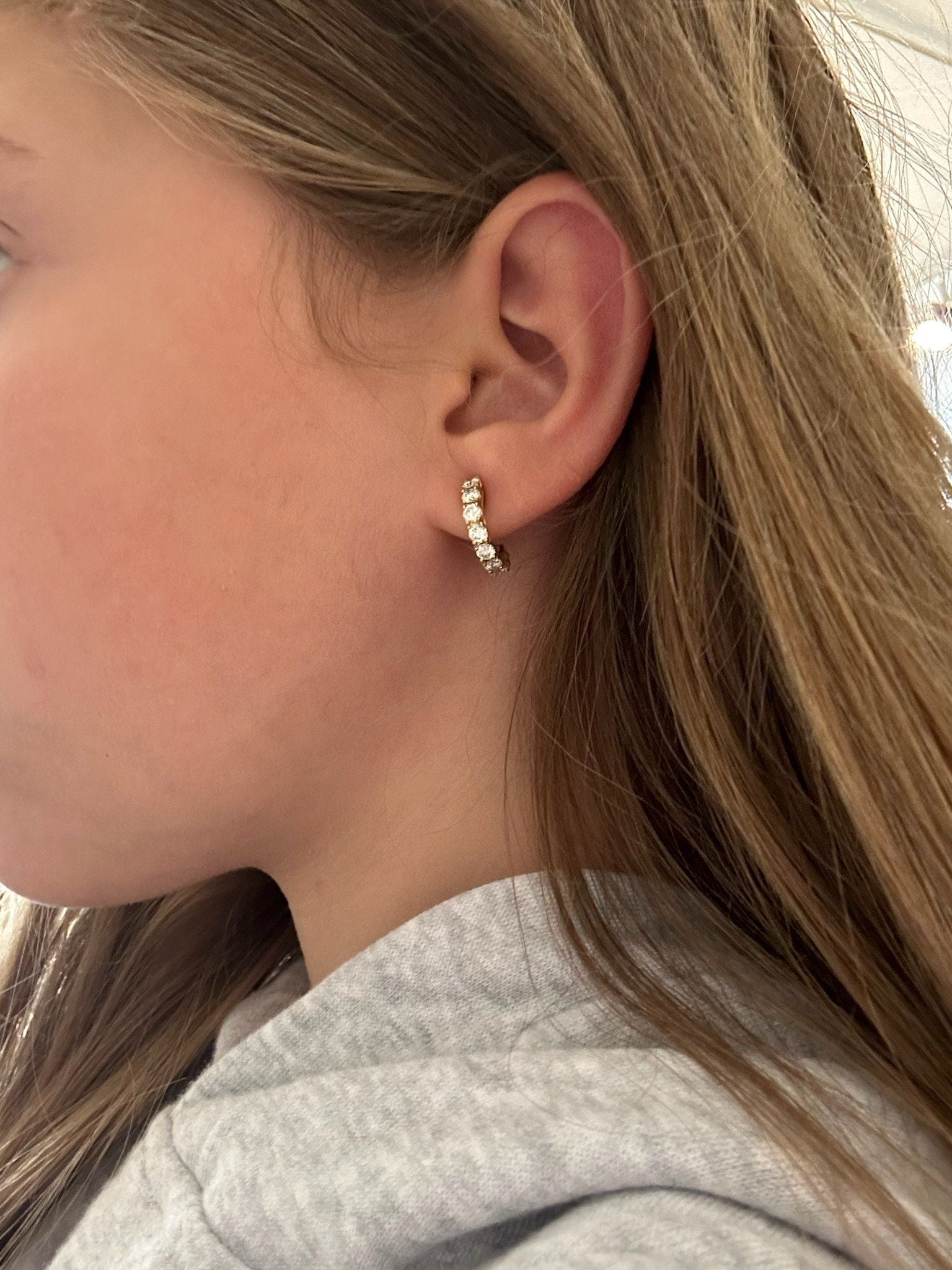 A yellow gold diamond set half hoop earring, modelled in an ear