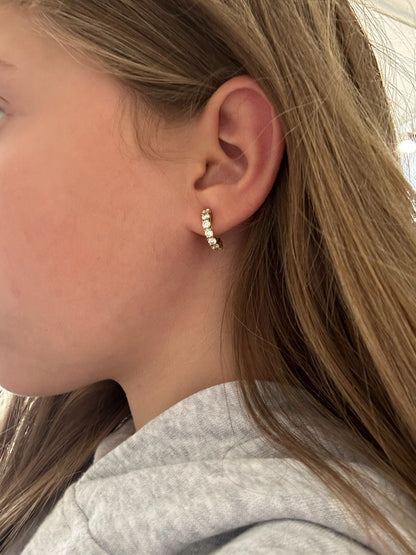 A yellow gold diamond set half hoop earring, modelled in an ear