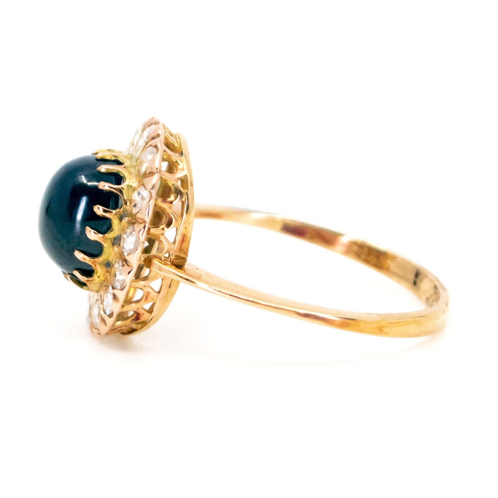 An oval cluster ring with a cabochon sapphire and diamond surround, in yellow gold