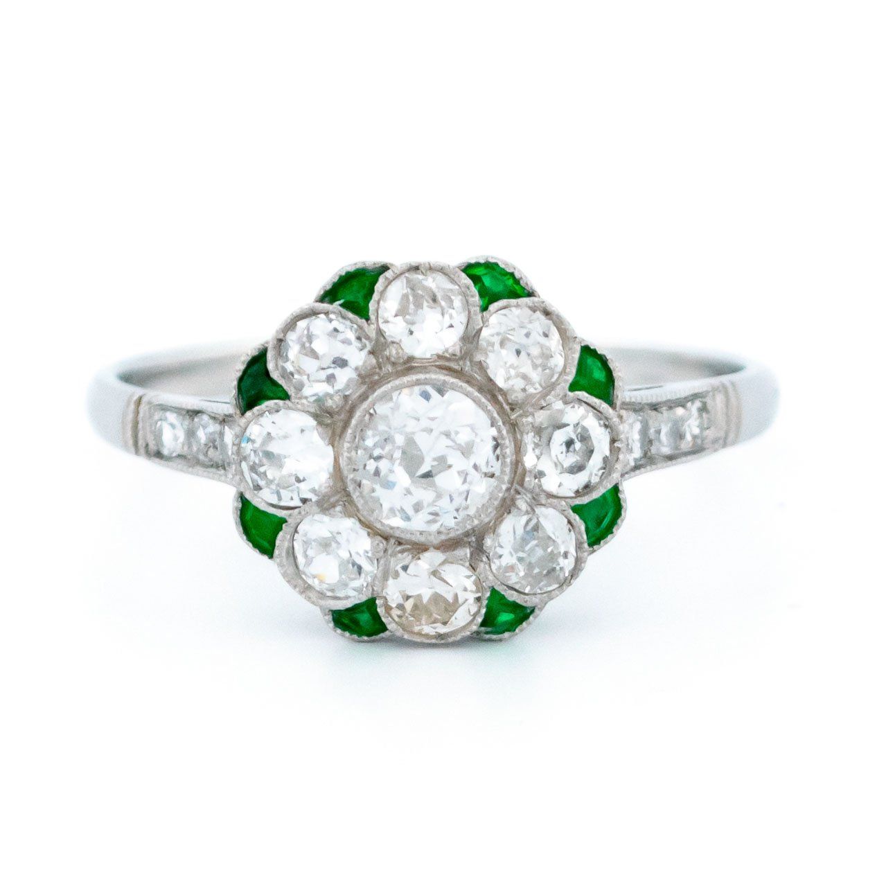 A diamond and emerald daisy cluster ring in platinum