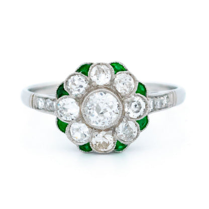 A diamond and emerald daisy cluster ring in platinum