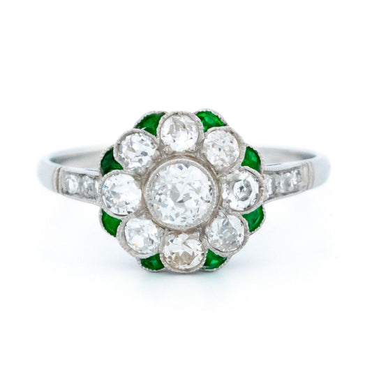 A diamond and emerald daisy cluster ring in platinum