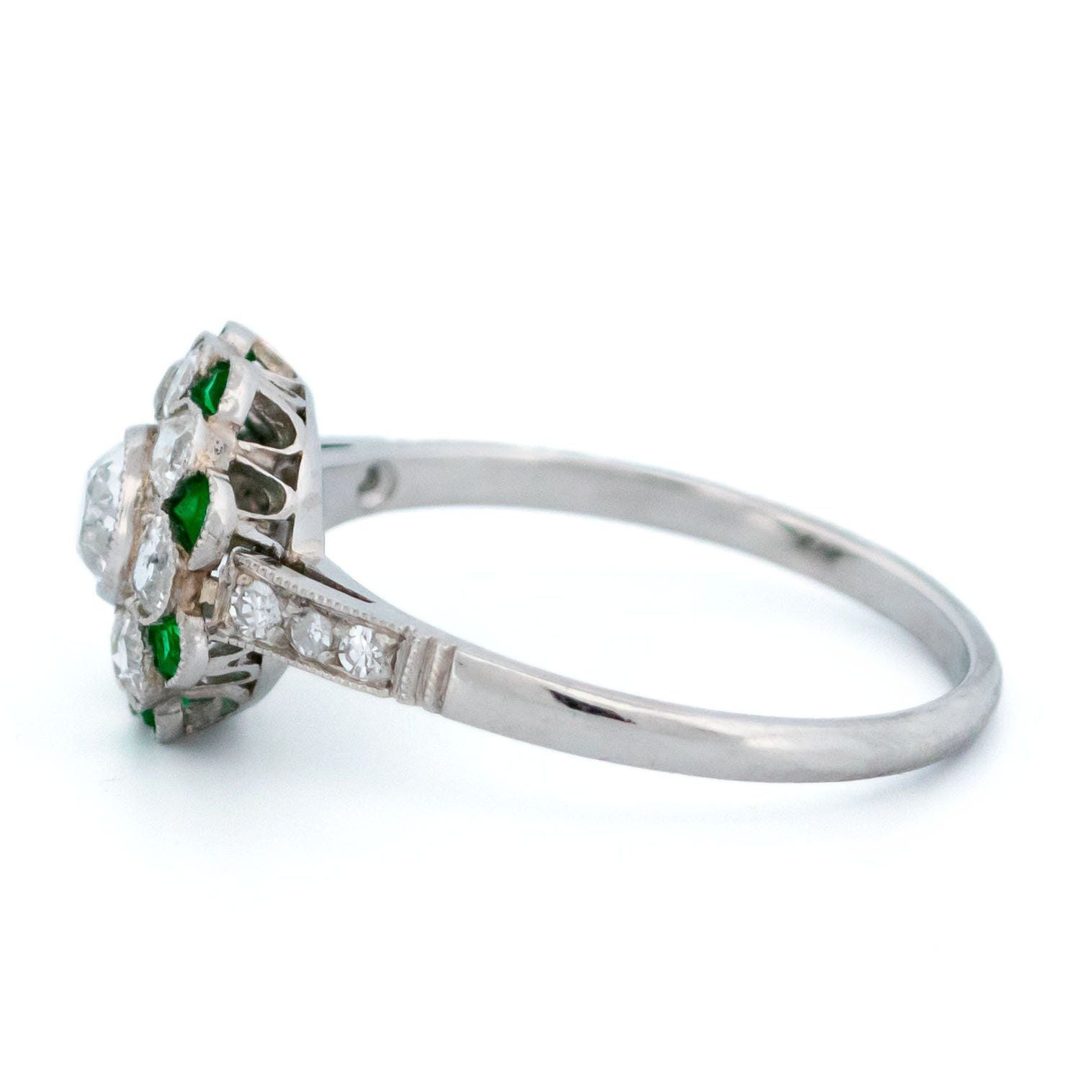 A diamond and emerald daisy cluster ring in platinum