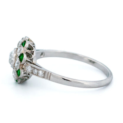 A diamond and emerald daisy cluster ring in platinum