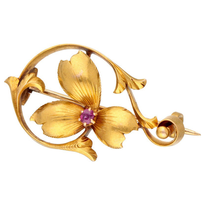 A yellow gold flower brooch with a pink sapphire centre